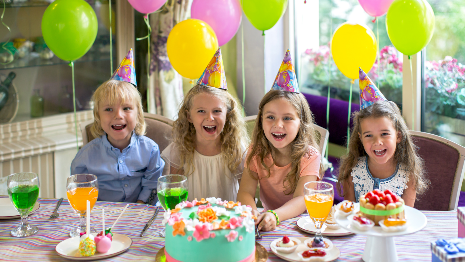 Enfants célébrant un anniversaire autour d’un gâteau décoré avec ballons colorés